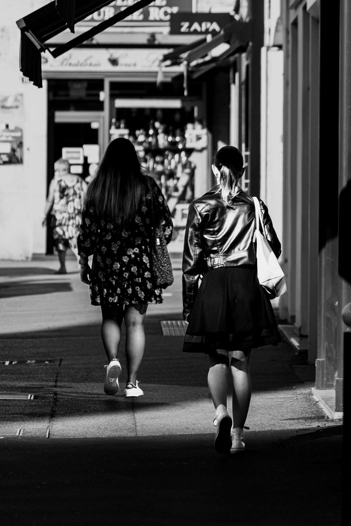 Black and white photo of women walking in urban street setting, a touch of nostalgia.