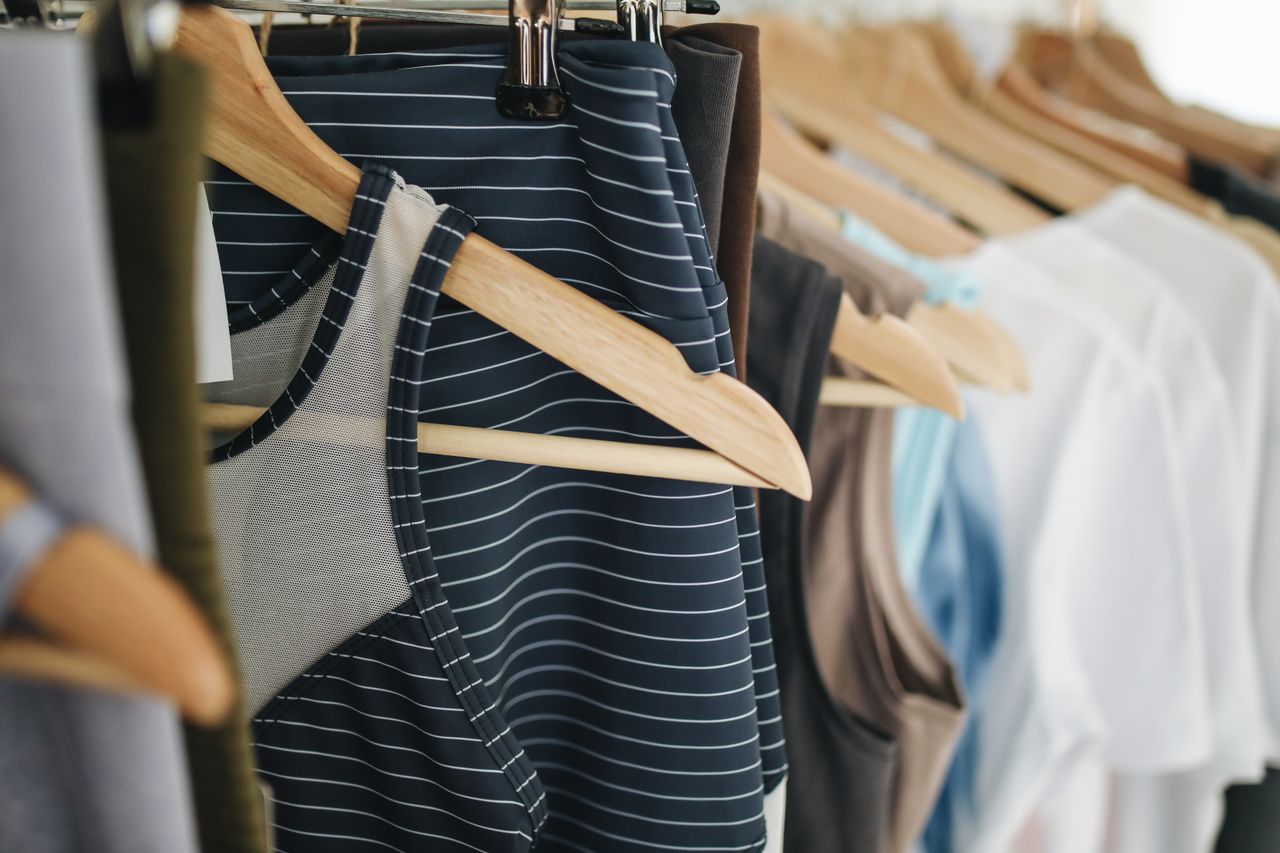 A close-up view of various clothing items hanging on wooden hangers in a retail store.