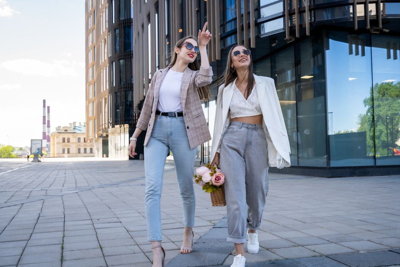 Two stylish women in sunglasses walking outdoors, embracing fashion trends.
